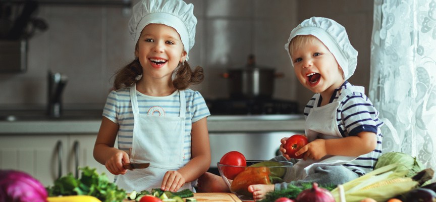 Healthy eating. Happy children prepares and eats vegetable salad in kitchen